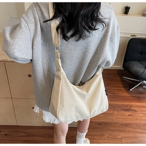Detail of cream-white canvas hobo bag showing textured fabric and silver zipper closure
