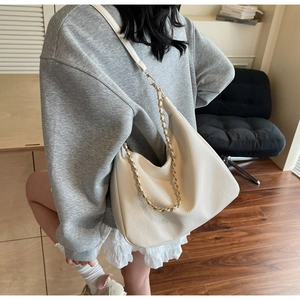 Detailed macro view of the cream tote bag showing pebbled leather texture and gold chain