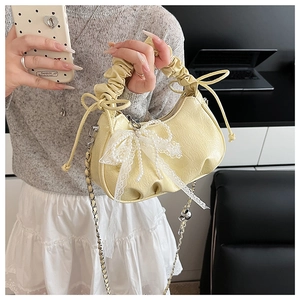 Détail du sac croissant jaune avec nœud en dentelle, perles et poignée froncée