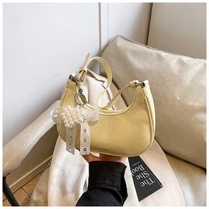 Detail of light yellow crescent shoulder bag with glossy pleated texture and pearl bow