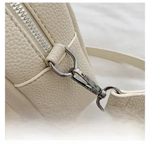 Detail of detachable metal hook and lychee texture cream leather on crossbody bag
