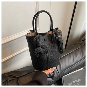 Detail of black pebbled leather bucket bag featuring a cute elephant charm and handle
