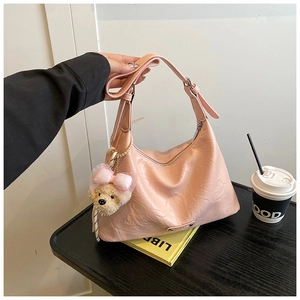 Détail du sac à bandoulière plissé rose avec charm d'ours en peluche et texture en PU