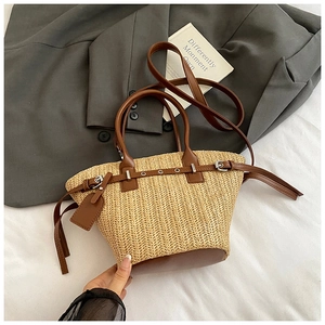 Top view of woven straw bucket bag with brown leather handles and metal buckle strap detail