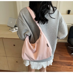 Detail of light pink canvas hobo bag showing the wide adjustable strap and crescent shape
