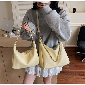 Detail of yellow lychee textured leather bags with gold chain straps in lifestyle setting