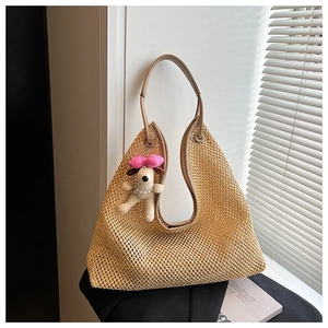 Close-up of straw woven tote bag with plush puppy charm and faux pearl necklace