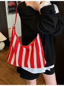 Sac fourre-tout en maille rayée rouge et blanc avec bandoulière en cuir porté par un modèle