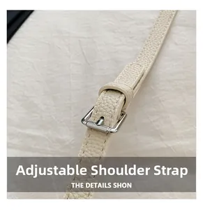 Close-up of adjustable cream leather shoulder strap with silver buckle and lychee grain