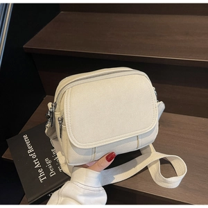 Detail van crème canvas crossbody tas met dubbele ritsen en een brede geweven schouderband
