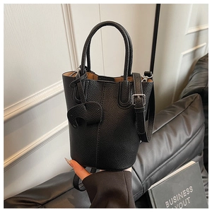 Detail of black lychee grain leather bucket bag with elephant charm and metal buckle