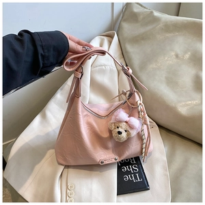 Détail du sac rose à texture plissée avec fermeture éclair argentée et bijou d'ours