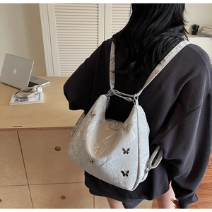 Close-up of stylish silver texture backpack with decorative metal butterfly accents