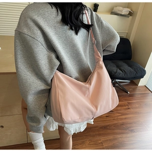 Detailed back view of model wearing a pink canvas hobo bag with adjustable strap