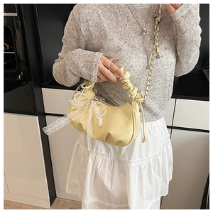 Détail du sac croissant jaune clair avec texture plissée et nœud en dentelle blanche