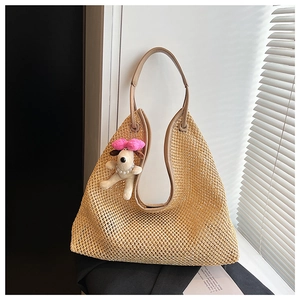 Detail of woven straw tote bag featuring brown leather straps and a cute puppy charm