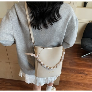 Sac seau beige chic avec chaîne foulard fleurie porté dans un style de vie décontracté