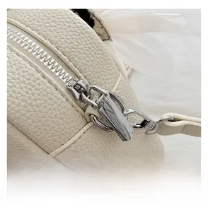 Close-up of smooth silver metal zipper and lychee pattern leather on cream boston bag