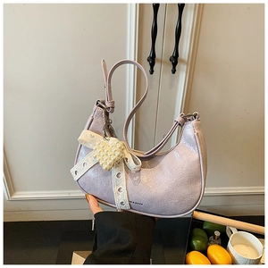 Close-up of light purple crescent bag with lace bow and heart-shaped pearl charm