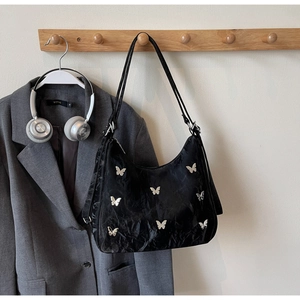 Detail of black pleated tote bag featuring nine silver butterfly metal accents on long strap