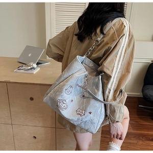 Détail du sac cabas bleu clair avec broderie chat et bandoulière porté par un mannequin
