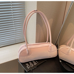 Light pink faux leather baguette bag on book showing smooth texture and silver zipper