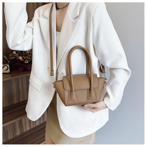 Detail of caramel leather handbag showing premium lychee texture and wing-shaped design