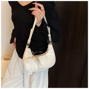 Detail of white hobo bag with pearl charms and lace bow on dark wood background