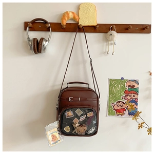 Detailed view of brown PU bag with transparent window and colorful pins and charms