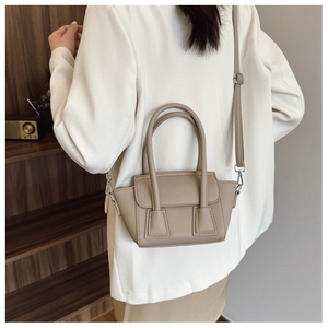 Detail view of khaki pebbled leather winged bucket bag with adjustable shoulder strap