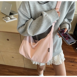 Close-up of large pink canvas hobo bag with wide strap and branded side label