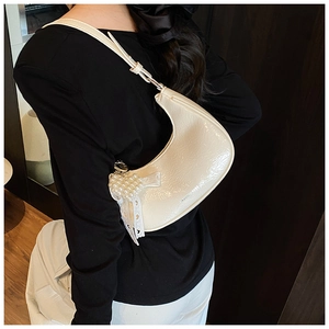 Detail of cream hobo bag with glossy pleated texture and pearl heart charm accessory