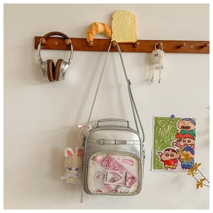 Silver PU leather ita bag with clear window and plush bunny charm on a wooden hook