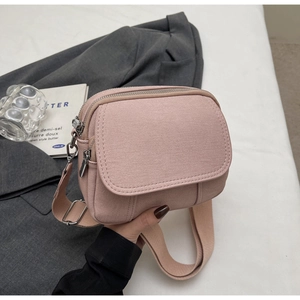 Detail van roze canvas crossbodytas met dubbele ritsen en een brede schouderband