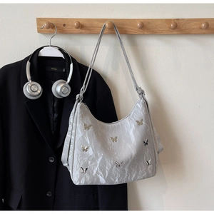 Detail of silver pleated hobo bag with butterfly metal accents on a wooden hook
