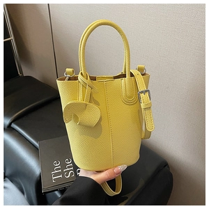 Close-up of a yellow litchi grain leather bucket bag with a cute elephant charm