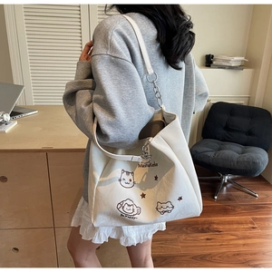 Détail du sac cabas blanc en toile avec imprimés de chats et bandoulière chaîne