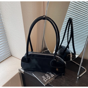 Detail of a black glossy leather Boston bag with silver zipper in a modern setting