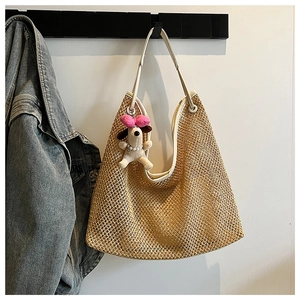 Detail of hand-woven straw tote bag texture with white leather strap and plush puppy charm