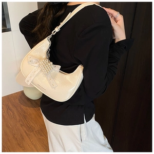 Detail of creamy white semi-moon bag featuring lace bow and pearl embellishments