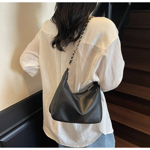 Close-up of black lychee grain hobo bag with gold metal chain and leather shoulder strap