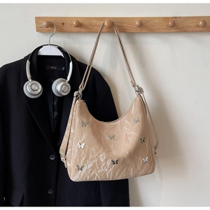Detail of beige hobo bag with silver metallic butterflies and adjustable strap