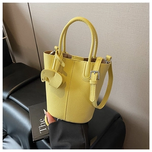 Detail of yellow lychee grain leather bucket bag with horse charm and slim strap
