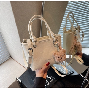 Close-up of cream mini tote bag with wrinkled leather texture and plush bear charm