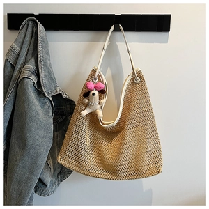 Detail of straw tote bag with white leather trim and a cute puppy plush pendant
