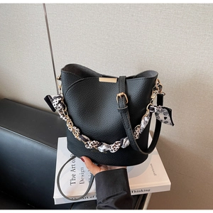 Detail of black lychee grain leather bucket bag with gold buckle and polka dot scarf handle