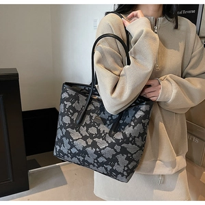 Detail of large tote bag featuring black and grey camouflage pattern and sturdy straps