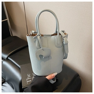 Detail of light blue bucket bag with pebble leather texture and elephant charm