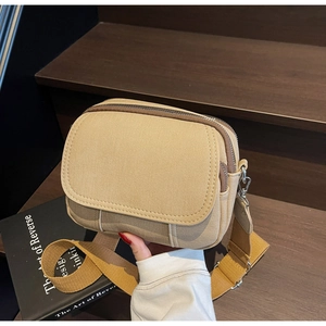 Detail van khaki canvas crossbodytas met dubbele ritsvakken en brede geweven schouderriem