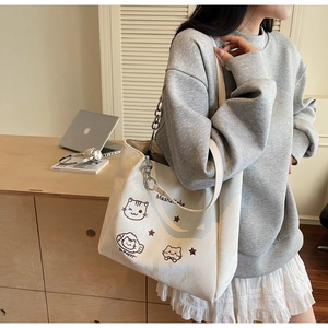 Détail d'un grand sac cabas blanc avec illustrations de chats et bandoulière en chaîne
